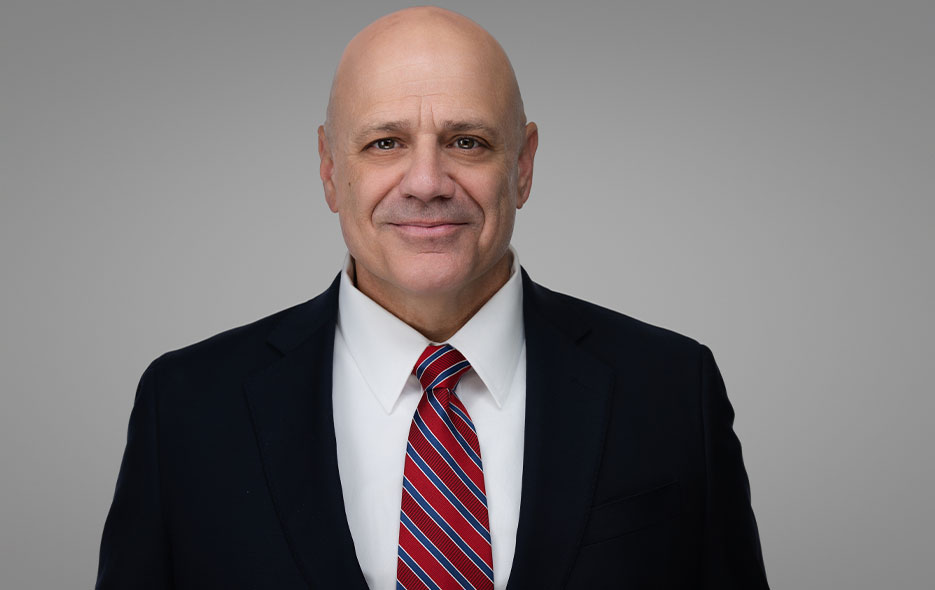 man with bald head in dark suit and tie with white shirt. posed for corporate headshot.